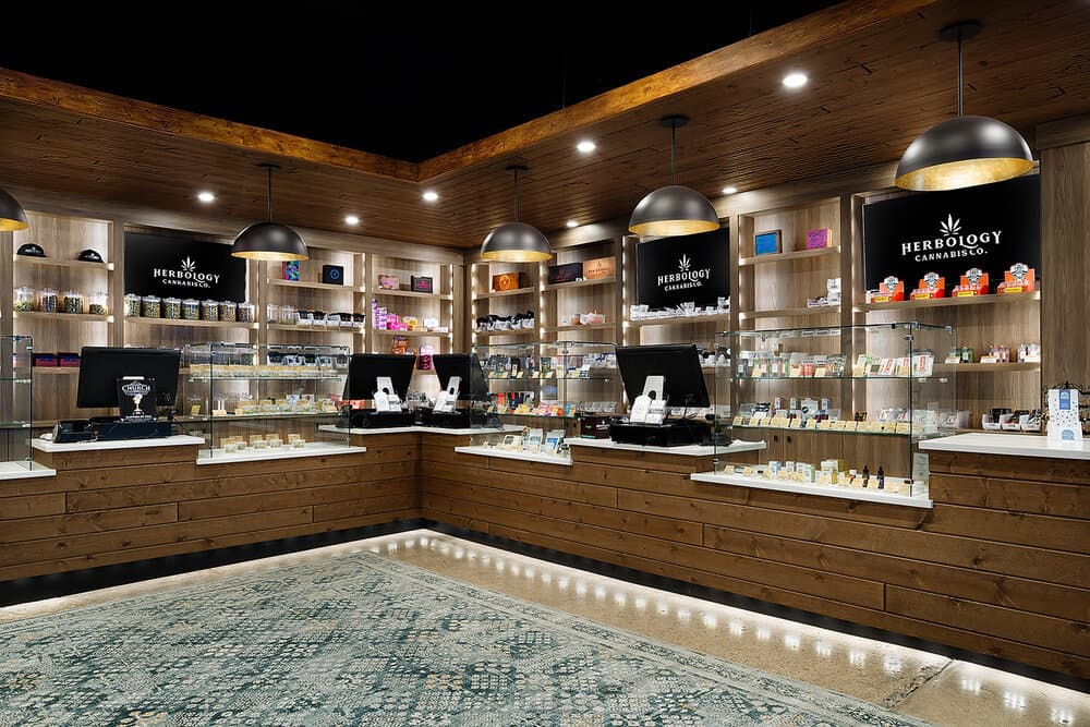 Inside Herbology Cannabis Co. – A Modern, Customer-Focused Cannabis Dispensary Interior of Herbology Cannabis Co. dispensary featuring well-lit product displays, modern wooden decor, and welcoming shopping environment